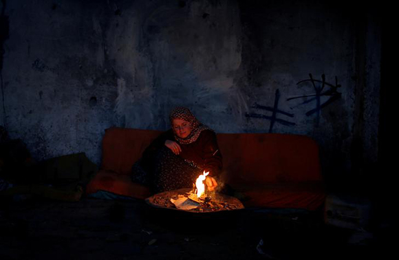  A Palestinian woman warms herself by a fire inside her house on a winter day, in the northern Gaza Strip Photo by Mohammed Salem 