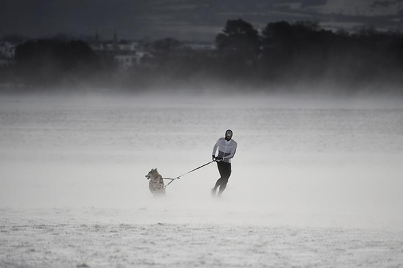  A man runs through the snow with his husky dog at the Phoenix Park in Dublin, Ireland Photo by Clodagh Kilcoyne 